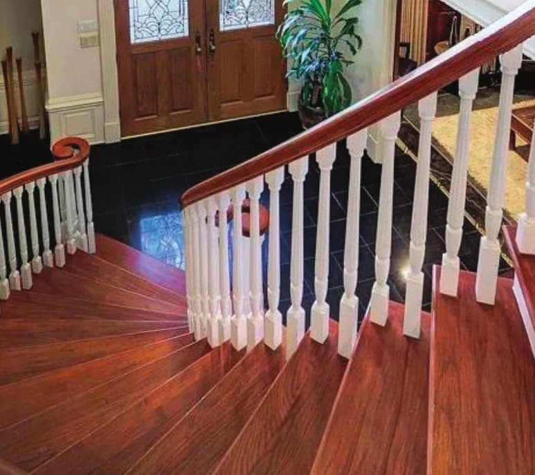Curved Bunker Hill staircase with white turned balusters and a stained hardwood volute