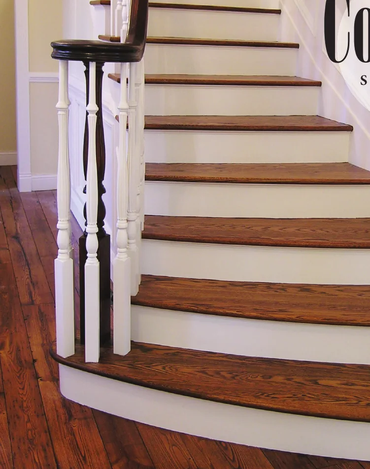 Country-style staircase with white turned balusters and a dark stained starting newel
