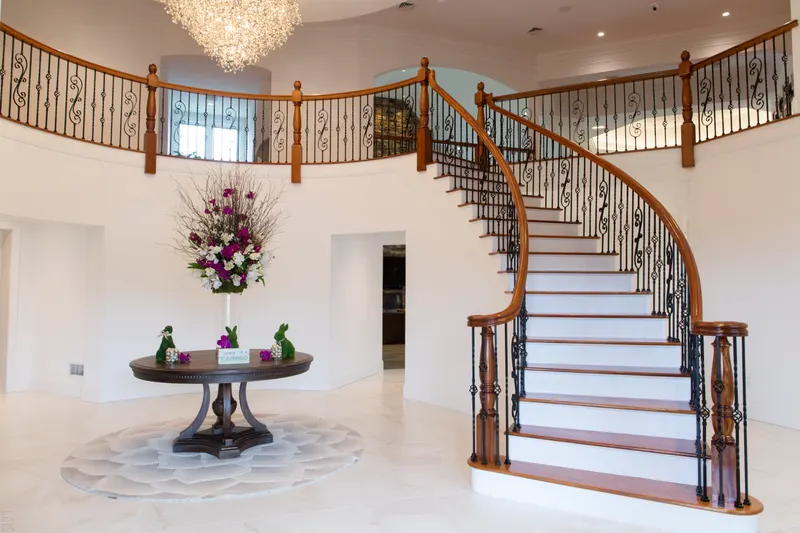 Sweeping curved staircase with wrought iron balusters in a two-storey entry