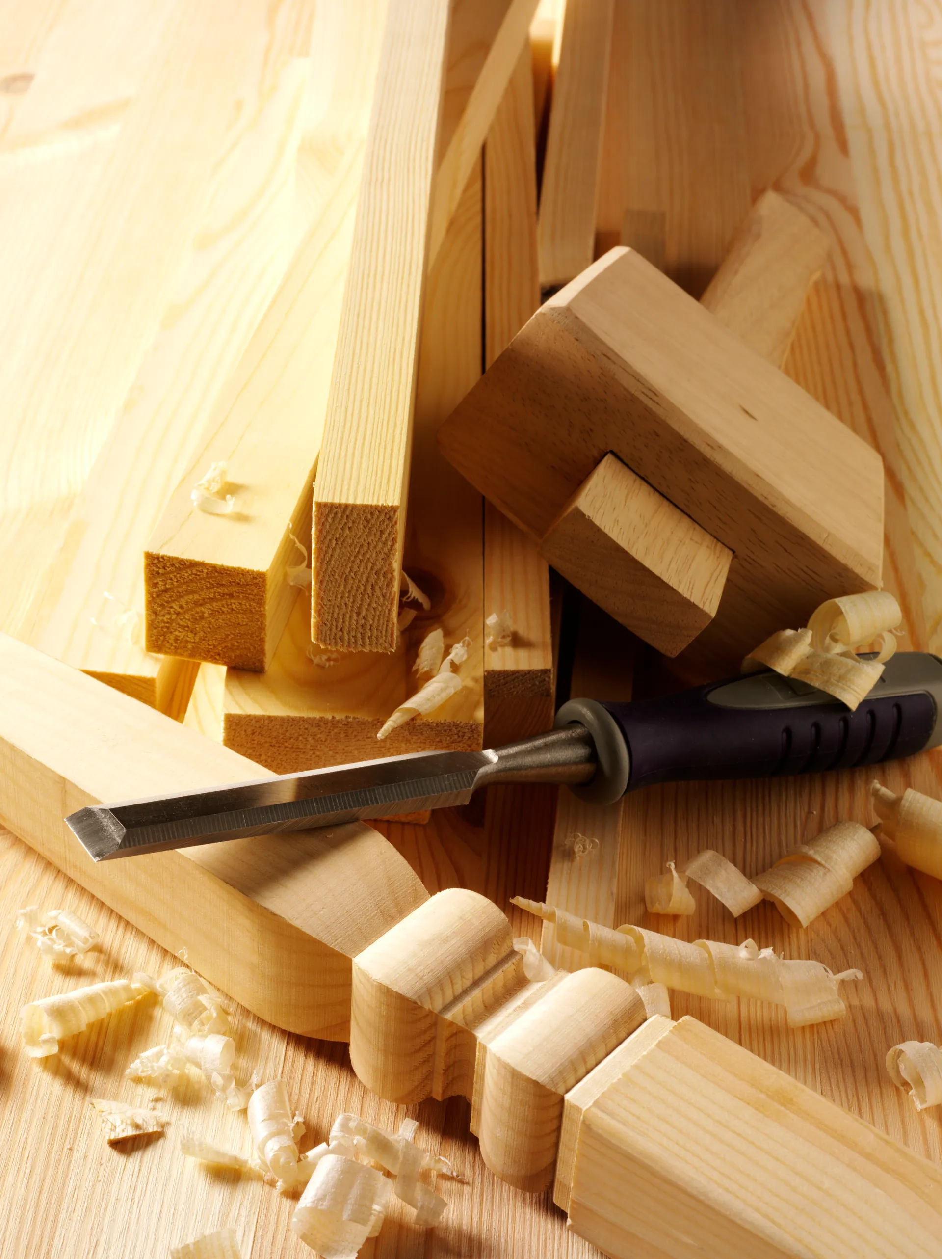A craftsperson working a wood component with a chisel and mallet
